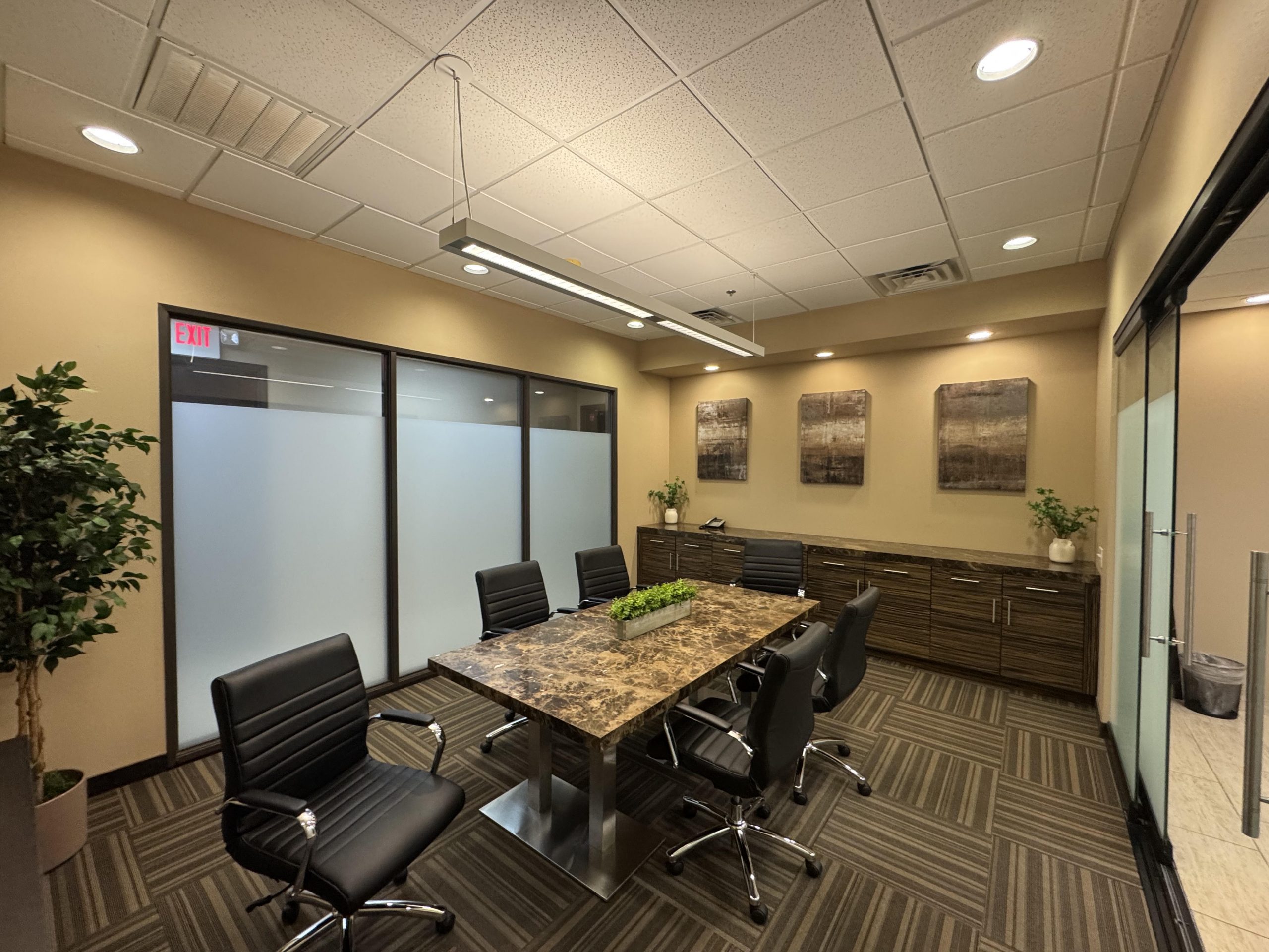 A professional-looking conference room containing a table surrounded by six office chairs.